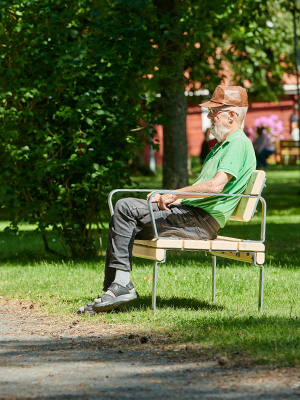 A man relaxing in the park, siting on a wooden bench.